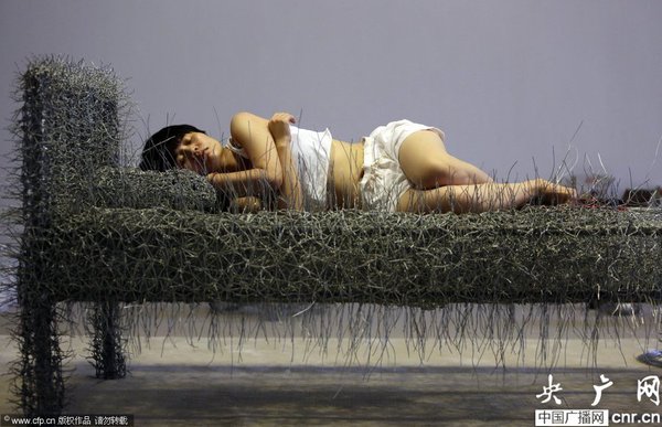 2014年8月11日，北京，中國女藝術家周潔在北京現(xiàn)在畫廊的展廳睡在一個未完成的鐵絲床上，這一藝術項目被命名為“36天”，而這36天里，她可以正常進食、洗漱、如廁，以及玩手機等。