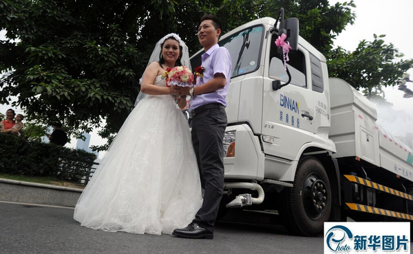 05 2014年8月15日，重慶，一對新人結(jié)婚用12輛環(huán)衛(wèi)車灑水迎親。新郎新娘在灑水車前合影。