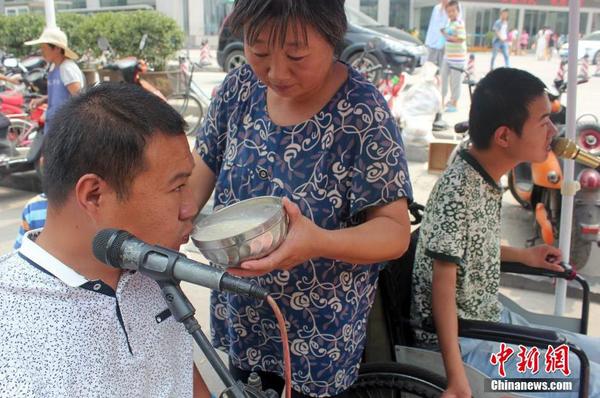 每天起床后便匆匆來到街頭“賣唱”，呂愛梅只能把面湯熬好在小強(qiáng)和小猛唱歌間隙喂他們吃。馬義恒 攝