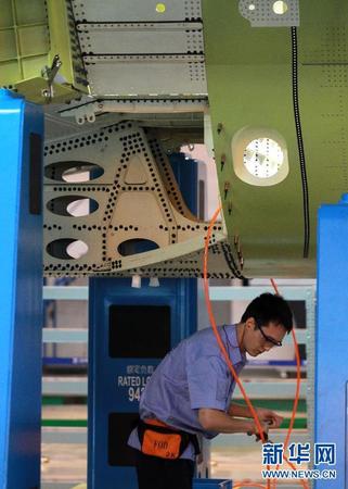 　 9月19日，技術(shù)人員在C919機體對合裝配線上工作。當日，C919國產(chǎn)大型客機首架機在中國商飛公司新落成的總裝制造中心正式開始機體對接，這標志著C919大型客機研制項目全面進入結(jié)構(gòu)總裝攻堅階段。項目力爭年底完成首架機機體結(jié)構(gòu)對接，2015年底實現(xiàn)首飛。新華社記者裴鑫 攝