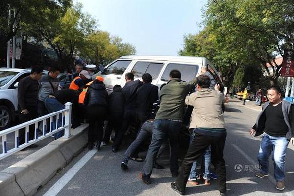 此時周圍路過的市民和附近商販紛紛趕來，十幾人用力抬起面包車，將老人救出。