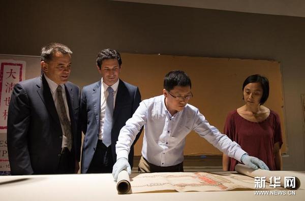 12月8日，在位于澳大利亞堪培拉的澳大利亞國(guó)家圖書(shū)館展廳，來(lái)自中國(guó)國(guó)家圖書(shū)館古籍部文獻(xiàn)修復(fù)組的朱振彬（右二）展開(kāi)《大清門(mén)至坤寧宮中一路立樣糙底》。
