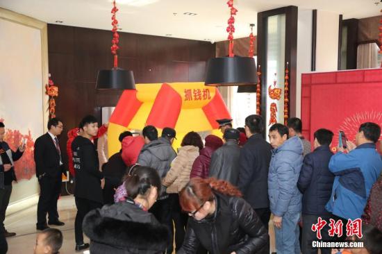 資料圖：2016年2月27日，山東東營(yíng)，看房的市民在商家設(shè)置的“搶錢機(jī)”內(nèi)搶著飛舞的人民幣，搶到的人民幣歸市民所有。由于房地產(chǎn)市場(chǎng)低迷，山東東營(yíng)的某樓盤為了吸引前來(lái)看房的市民，在售樓處安裝了“搶錢機(jī)”，看房的市民排成長(zhǎng)隊(duì)“搶錢”，用真金白銀刺激看房客。 圖片來(lái)源：視覺(jué)中國(guó)