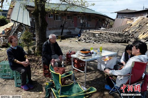 當(dāng)?shù)貢r間4月17日，日本熊本縣震后見聞。一家人圍坐在簡易桌旁吃飯，周圍都是倒塌的房屋。