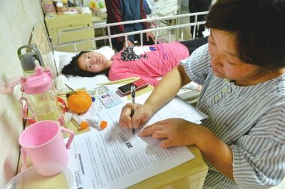 小琴躺在病床上輕微抽搐，媽媽在一旁填寫申請表希望能夠得到資助給女兒看病。京華時報記者王海欣攝