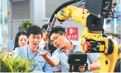 近日，在哈爾濱國際裝備制造業(yè)博覽會上，一家參展企業(yè)工作人員（右）在介紹機械臂。新華社記者 王 松攝