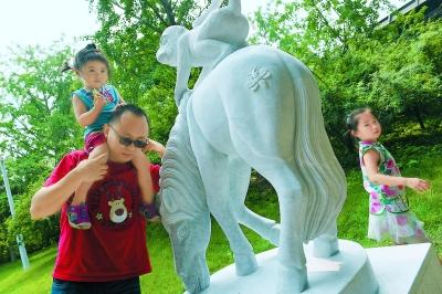 排隊(duì)購買“猴年馬月”特色郵品后，人們喜歡摸一摸“馬上封侯”的雕塑，為家人祚福。