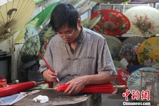 油紙傘傳人畢六福正在為油紙傘上色。 鄒立楊 攝 鄒立揚(yáng) 攝