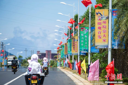 6月24日，海南省文昌市龍樓鎮(zhèn)街道兩側(cè)五星紅旗迎風(fēng)飄揚(yáng)，火箭“首發(fā)”宣傳廣告隨處可見。長征七號運(yùn)載火箭發(fā)射日期臨近，中國首個(gè)濱海航天發(fā)射中心——文昌航天發(fā)射場所在地海南省文昌市龍樓鎮(zhèn)將迎來“首發(fā)”，中國的“卡納維拉爾角”正揭開神秘面紗。中新社記者 駱云飛 攝