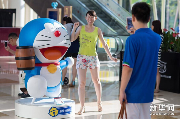 7月31日，一名市民在哆啦A夢卡通造型旁拍照。1