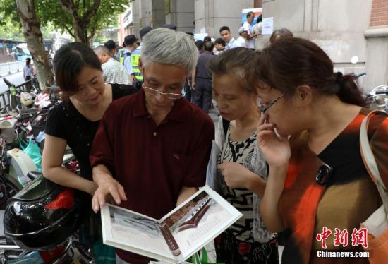 資料圖：幾位杭州市民欣賞已買到的“G20杭州峰會明信片”。 中新社記者 王剛 攝