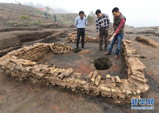 在桐木嶺礦冶遺址，考古人員查看用廢棄坩堝壘筑的房屋遺址（11月18日攝）。