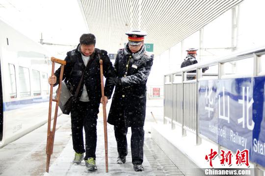 圖為鐵路工作人員幫助旅客進(jìn)站?！∏劓z