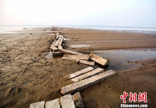 　　近年來，當(dāng)鄱陽湖水位下降至枯水位時，石橋就會露出水面，成為當(dāng)?shù)匾痪?。圖為游人在古橋上行走。12月23日攝　傅建斌　攝