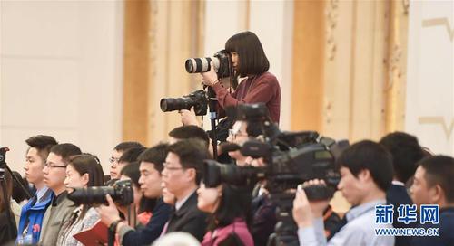 3月7日，一名女記者在十二屆全國(guó)人大五次會(huì)議江蘇代表團(tuán)全體會(huì)議上采訪拍攝。在兩會(huì)會(huì)場(chǎng)內(nèi)外，女代表、女委員、女工作人員、女記者在工作中盡職盡責(zé)，展現(xiàn)著自己的風(fēng)采。 新華社記者陳曄華攝