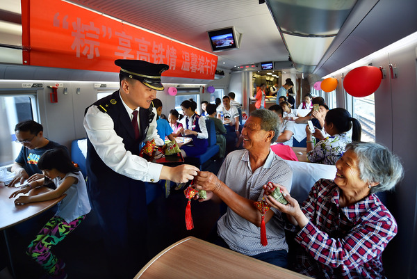 北京鐵路局天津客運(yùn)段值乘的廈門北至北京南G324次列車長(zhǎng)為老年旅客送上粽子與香囊紀(jì)念品。