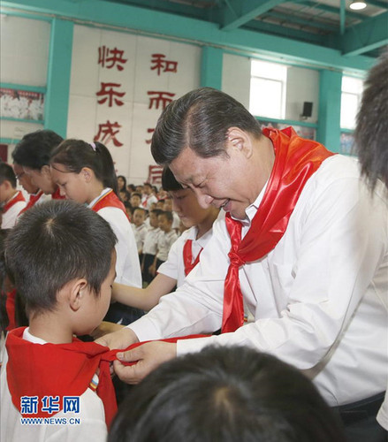2014年5月30日，在北京市海淀區(qū)民族小學(xué)的少先隊入隊儀式上，習(xí)近平為新少先隊員系上紅領(lǐng)巾。新華社記者鞠鵬攝