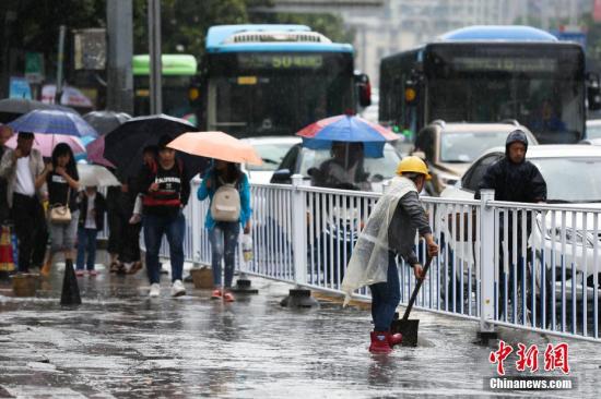 資料圖：行人在雨中出行。 黃芷昕 攝