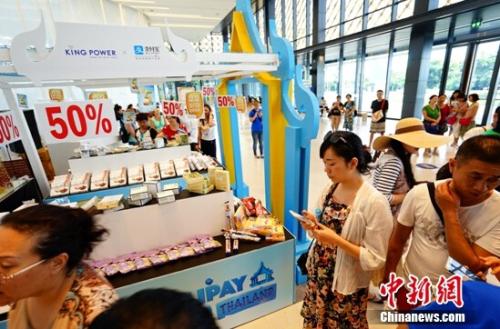 資料圖：某消費(fèi)者在線下商品展臺(tái)前選購(gòu)。