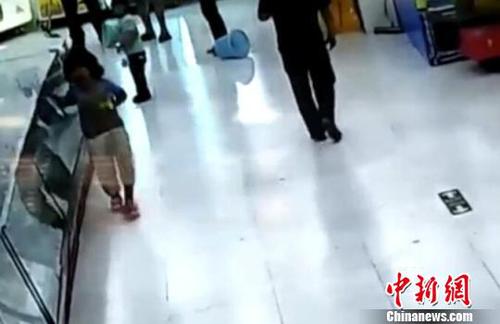 被市民拉開后，女童扶著柜臺一瘸一倒的離去。(視頻截圖)