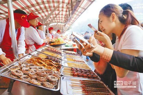 北京一“蟲子宴”攤位，擺滿串蛇、蜈蚣、螞蚱、蜘蛛等，不少食客拿出手機(jī)拍照。（臺(tái)灣中時(shí)電子報(bào)）