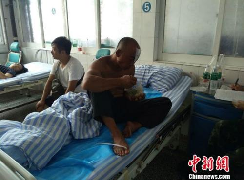 獲救漁民丁兆蘭光著上身，左額頭用紗布包著，正在吃著醫(yī)務(wù)人員送來的午飯。于從文 攝