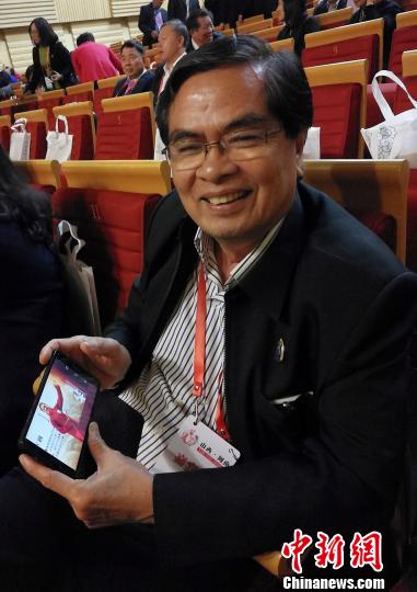 泰國華文民校協(xié)會中文秘書、泰國明滿學(xué)校校長陳松向記者展示學(xué)生參加“漢語橋”比賽的照片?！罱苡?攝