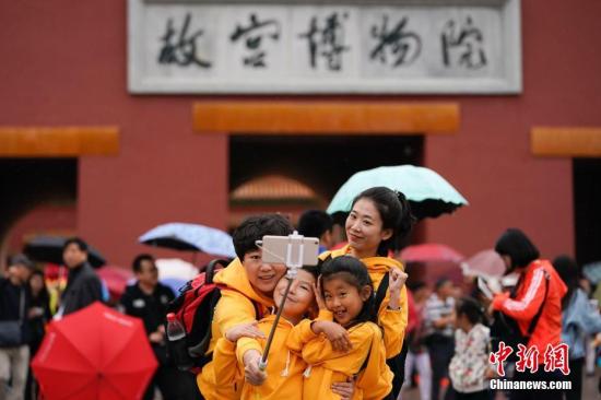 10月2日，北京小雨，游客在故宮博物院游覽。根據(jù)國(guó)家旅游局?jǐn)?shù)據(jù)中心綜合測(cè)算，中國(guó)國(guó)慶假期首日，全國(guó)當(dāng)天共接待游客1.13億人次，同比增長(zhǎng)10.5%，實(shí)現(xiàn)旅游收入965億元，同比增長(zhǎng)12.2%。<a target='_blank' href='http://www.chinanews.com/'>中新社</a>記者 杜洋 攝