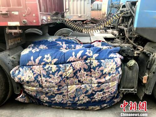 圖為卡車司機(jī)用棉被為卡車“取暖”。　鐘欣 攝