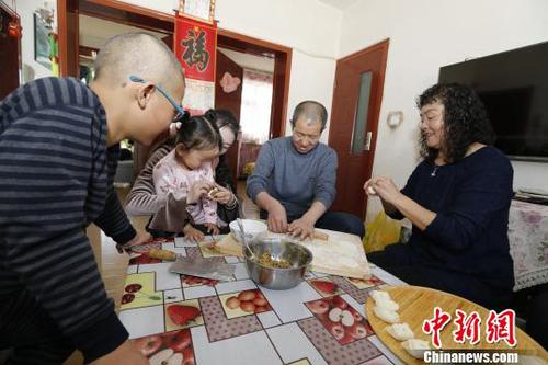 圖為彭秀芳“一家四口”包餃子。(抱著玲玲的是福利院工作人員) 胡貴龍 攝