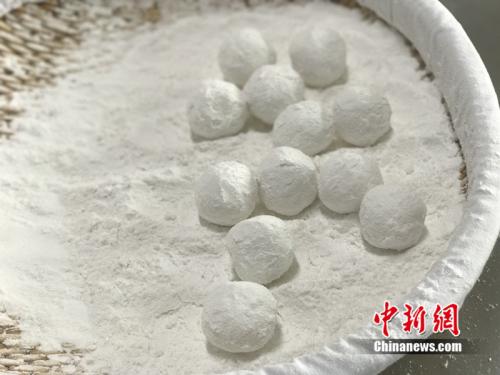 "制作元宵時(shí)，首先要將餡料做好，沾上水，再投進(jìn)盛滿糯米粉的笸籮內(nèi)搖。<a