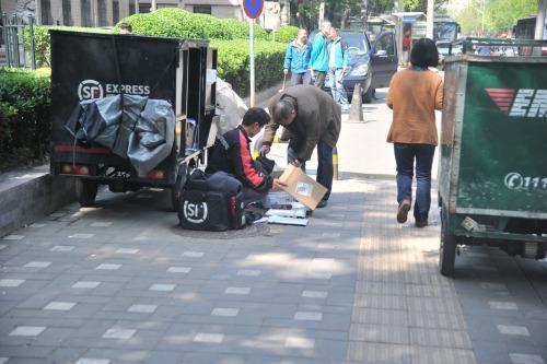 圖為快遞小哥在路邊配送快遞。呂春榮 攝