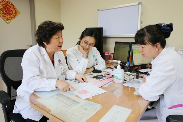 廖秦平在門診中和醫(yī)生一起討論病例。楊欣 攝
