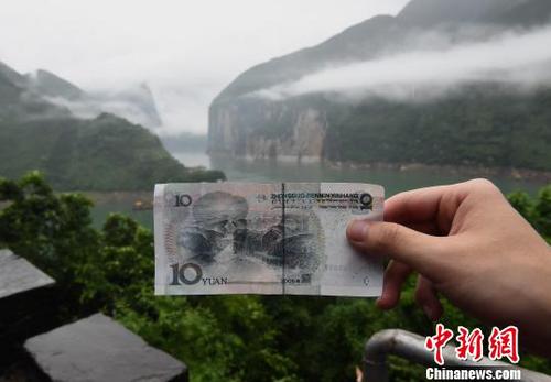 圖為游客在人民幣十元背景圖實景地駐足參觀，并拍照留念?！≈芤恪z