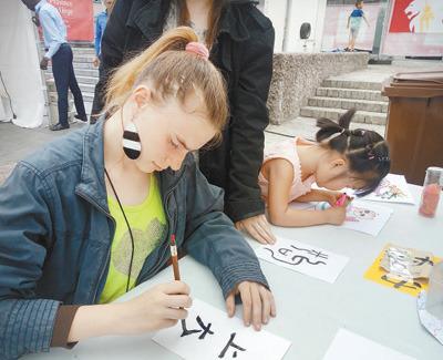 中國僑網(wǎng)6月10日，為期4天的第三屆比利時列日省“中國城會”活動落下帷幕。圖為列日大學的學生在活動現(xiàn)場學習書法。 本報記者 任 彥攝 