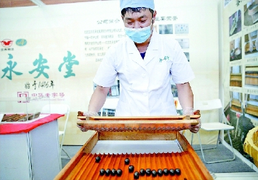 ▲圖為工作人員在活動現(xiàn)場向觀眾展示中藥蜜丸制作工藝。