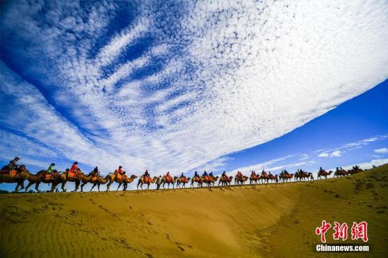 資料圖：甘肅敦煌鳴沙山月牙泉景區(qū)藍天、白云、黃沙相映成趣，每天吸引數(shù)萬中外游客觀光游覽。 王斌銀 攝