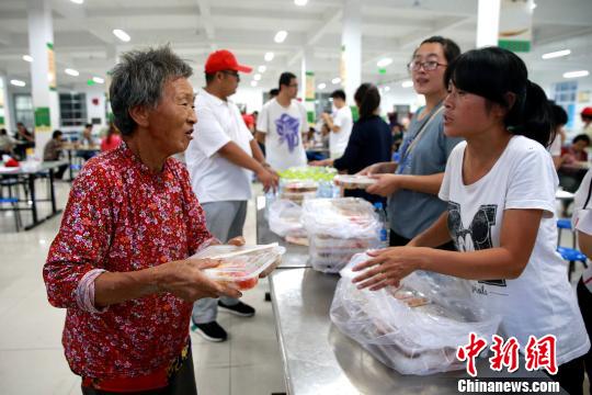 8月24日，志愿者在濰坊壽光市營(yíng)里鎮(zhèn)第二初級(jí)中學(xué)安置點(diǎn)為災(zāi)民發(fā)放救援物資?！×籂?攝