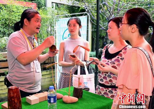 臺灣雕刻藝術(shù)家、臺灣木戀石文化藝術(shù)有限公司創(chuàng)辦人黃守堃(左一)向觀眾介紹自己的雕刻作品。記者劉可耕 攝