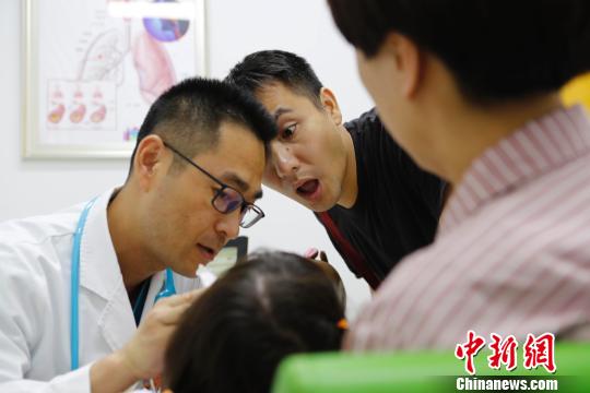 門診醫(yī)生正在耐心的給家長講解孩子的病情?！∫罅⑶凇z