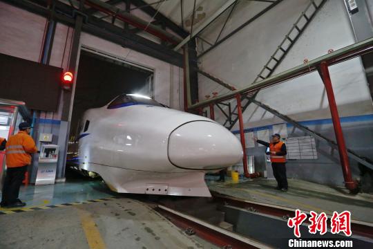 一列動(dòng)車組駛?cè)胲噹?kù)，機(jī)械師位列兩邊檢查車體外觀?！《〔?攝