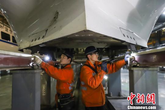動(dòng)車組機(jī)械師正在檢查動(dòng)車組底部組件?！⌒?攝