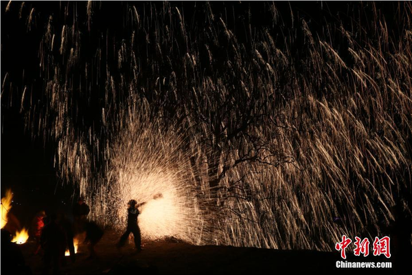 該村“打樹花”的習(xí)俗已延續(xù)了近600年，村民將生鐵融成鐵水后，再用特制的木板將鐵水擊打至樹上，頓時(shí)綻放出萬(wàn)點(diǎn)“鐵花”。中新社記者 陳昊 攝