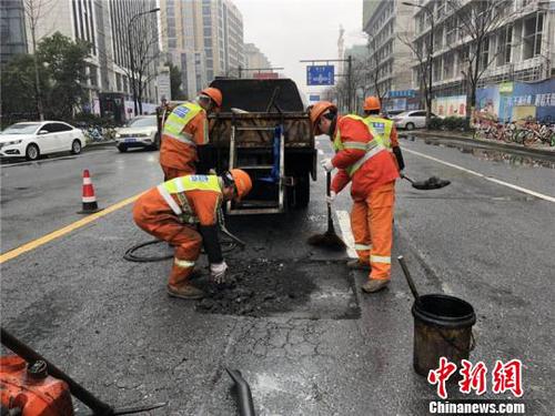 環(huán)衛(wèi)工人修補雨天侵蝕的瀝青路面?！∥骱^(qū)城管局提供 攝