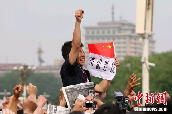 2008年5月19日，北京天安門廣場上的民眾為地震遇難者默哀，一位來自四川的男子高舉右手為家鄉(xiāng)加油。中新社記者 富田 攝