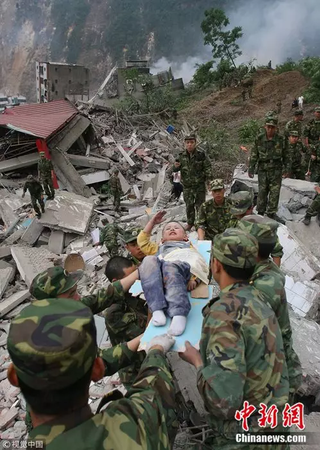 2008年5月13日，3歲的郎錚因為躺在擔(dān)架上向解放軍戰(zhàn)士敬禮。 楊衛(wèi)華 攝 圖片來源：視覺中國