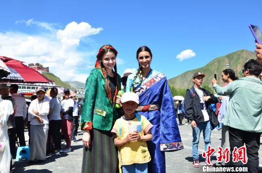 圖為身著藏族服裝的外籍模特比賽完與當(dāng)?shù)氐男『⒑嫌傲裟睢！◆數(shù)り?攝