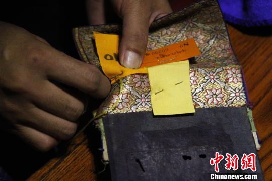 圖為羅布林卡管理處工作人員將編號縫在古籍外側(cè)?！≮w朗 攝