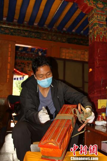 圖為西藏自治區(qū)古籍保護(hù)中心古籍保護(hù)部副主任才洛打開古籍進(jìn)行登記?！≮w朗 攝