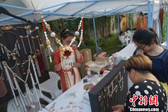 游客在首飾攤位前駐足?！堨蠚g 攝
